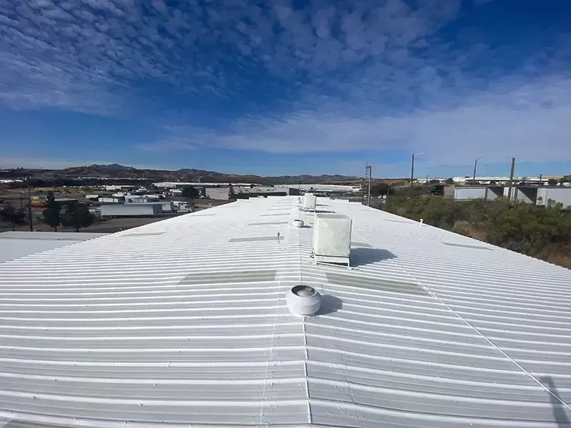 A white roof with a chimney on the side of a house.