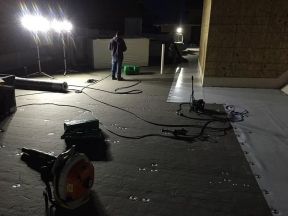 A man is standing on a roof at night.