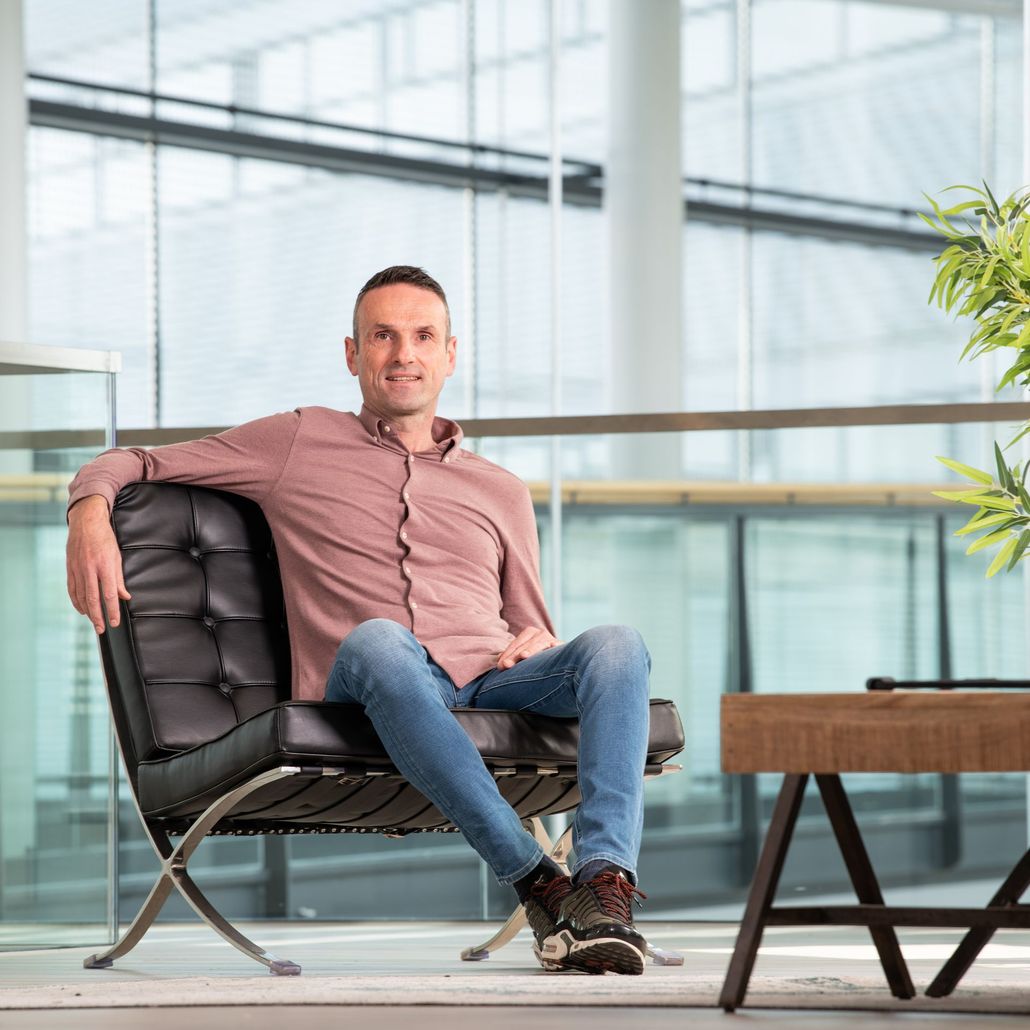 A man is sitting in a chair in front of a window.