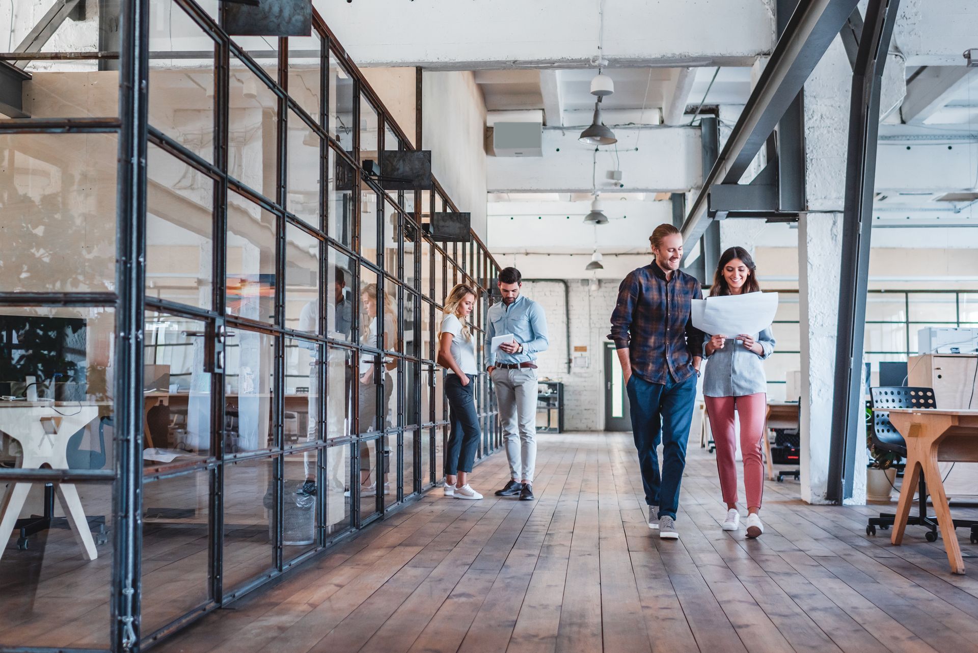 Professionals walking and talking in the hallway of a modern office space. 
