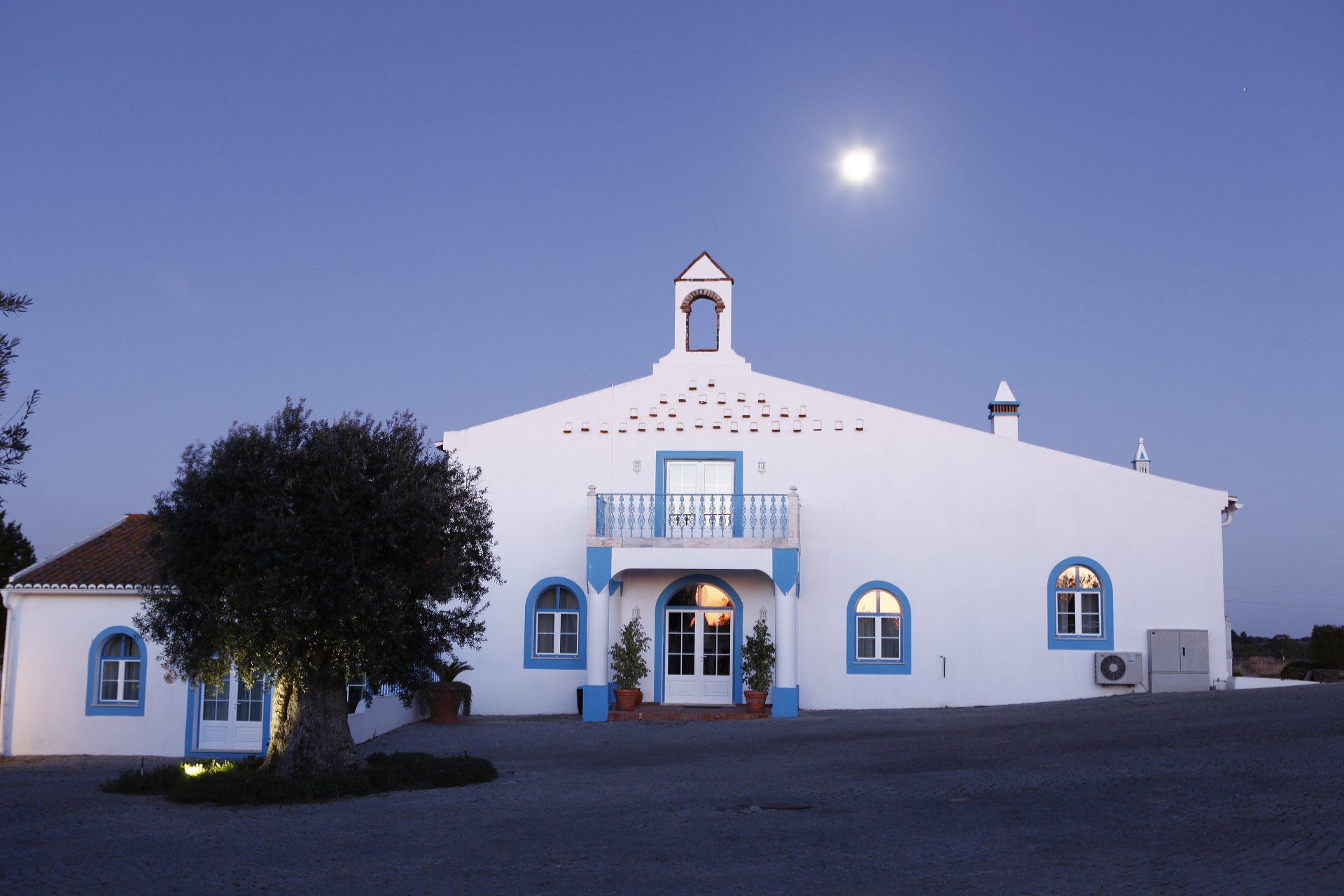 White building with blue trim under a moonlit sky.