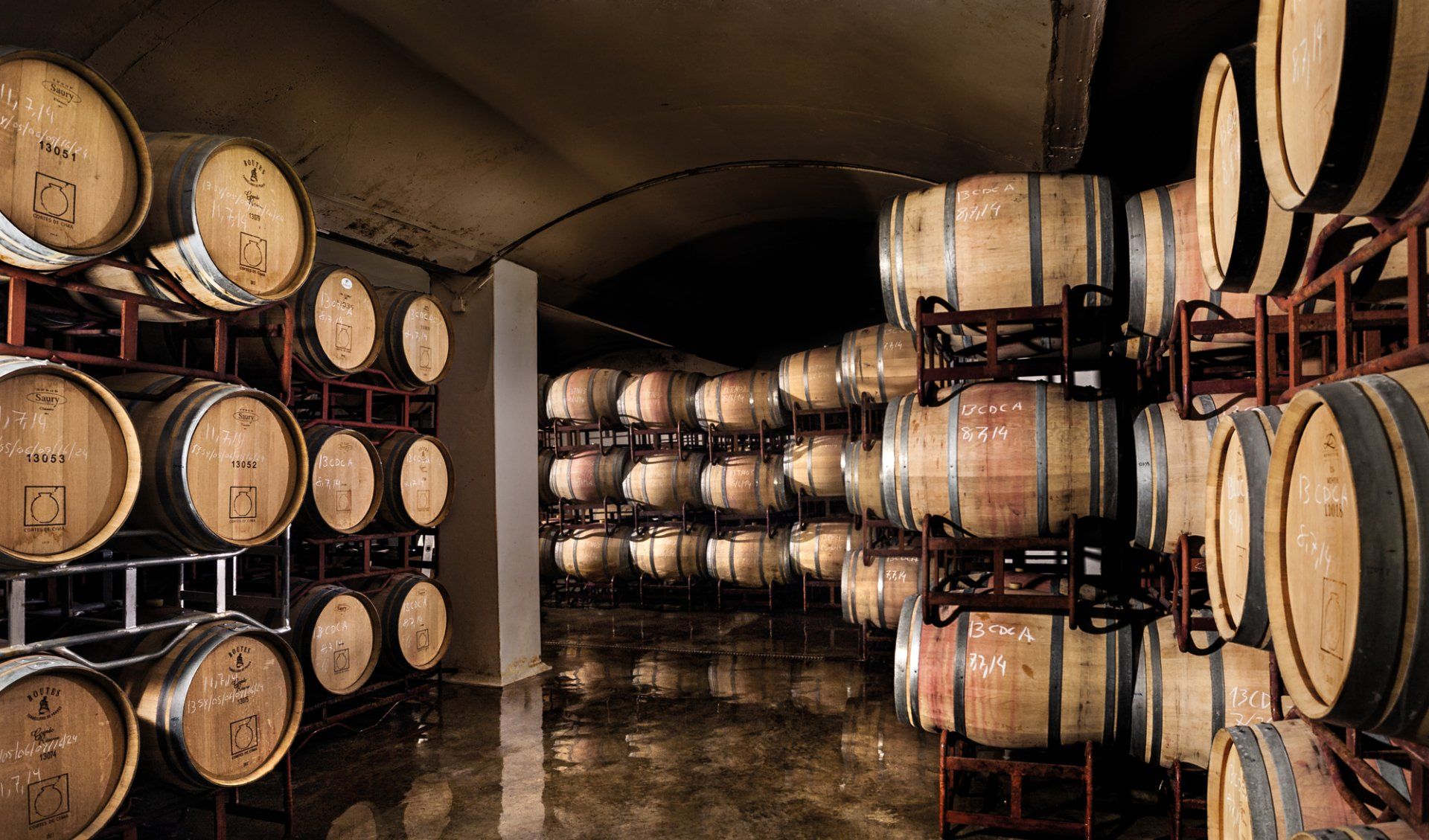 Wine barrels stacked in a dimly lit cellar.