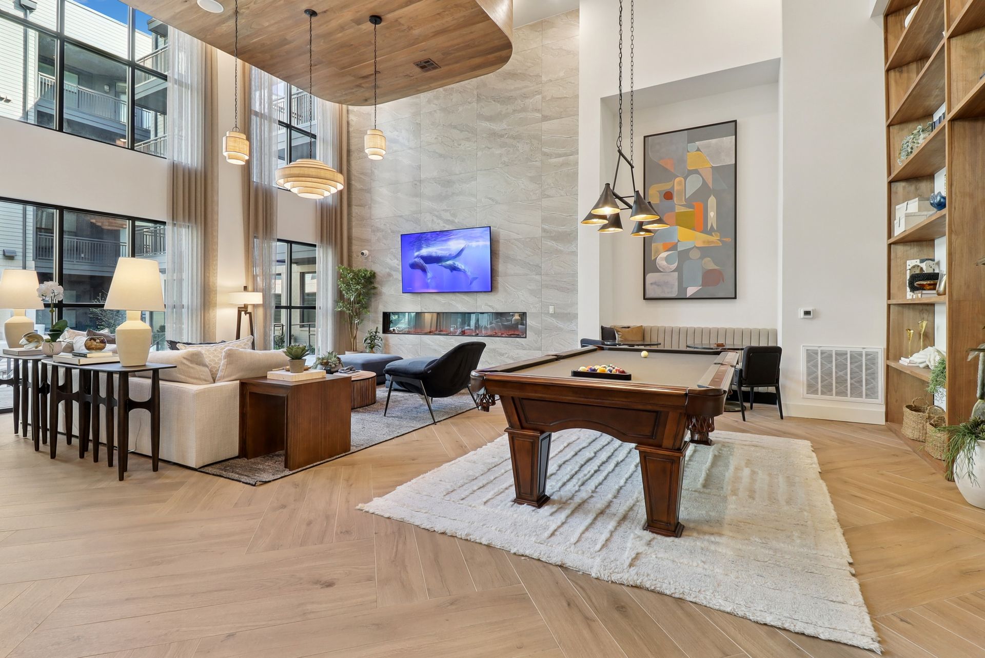 Spacious modern lounge area with pool table, large windows, and decorative lighting.