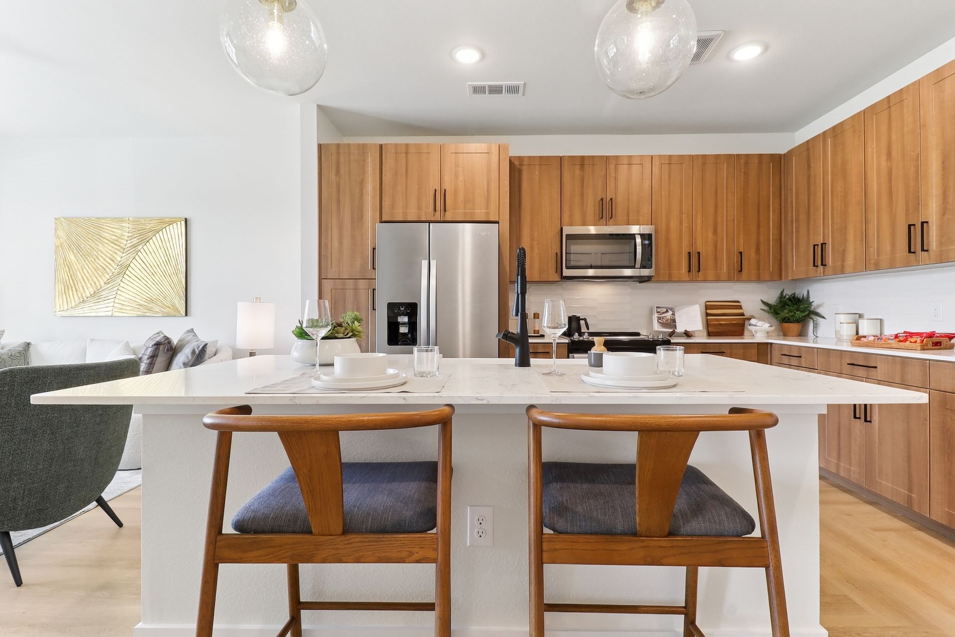 A kitchen with stainless steel appliances , wooden cabinets , a table and chairs.