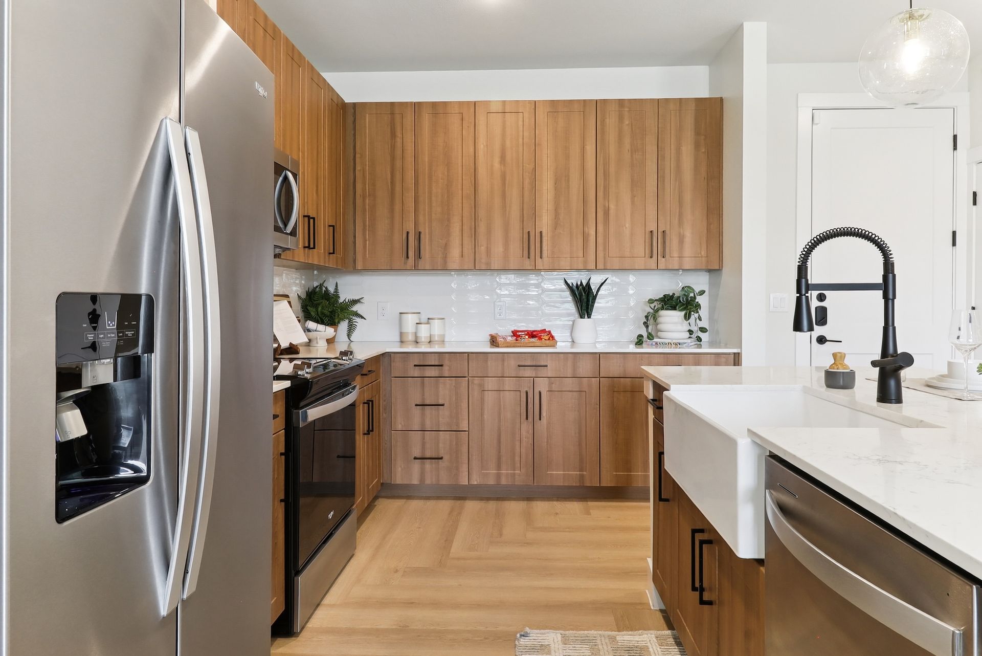 A kitchen with stainless steel appliances , wooden cabinets , a sink and a refrigerator.