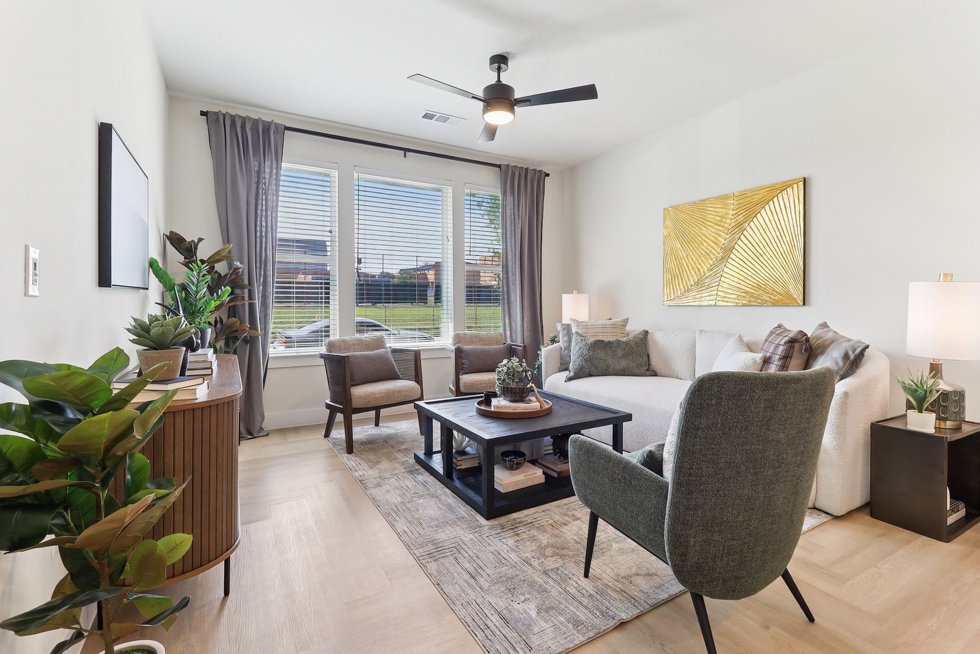 A living room with a couch , chairs , coffee table and ceiling fan.