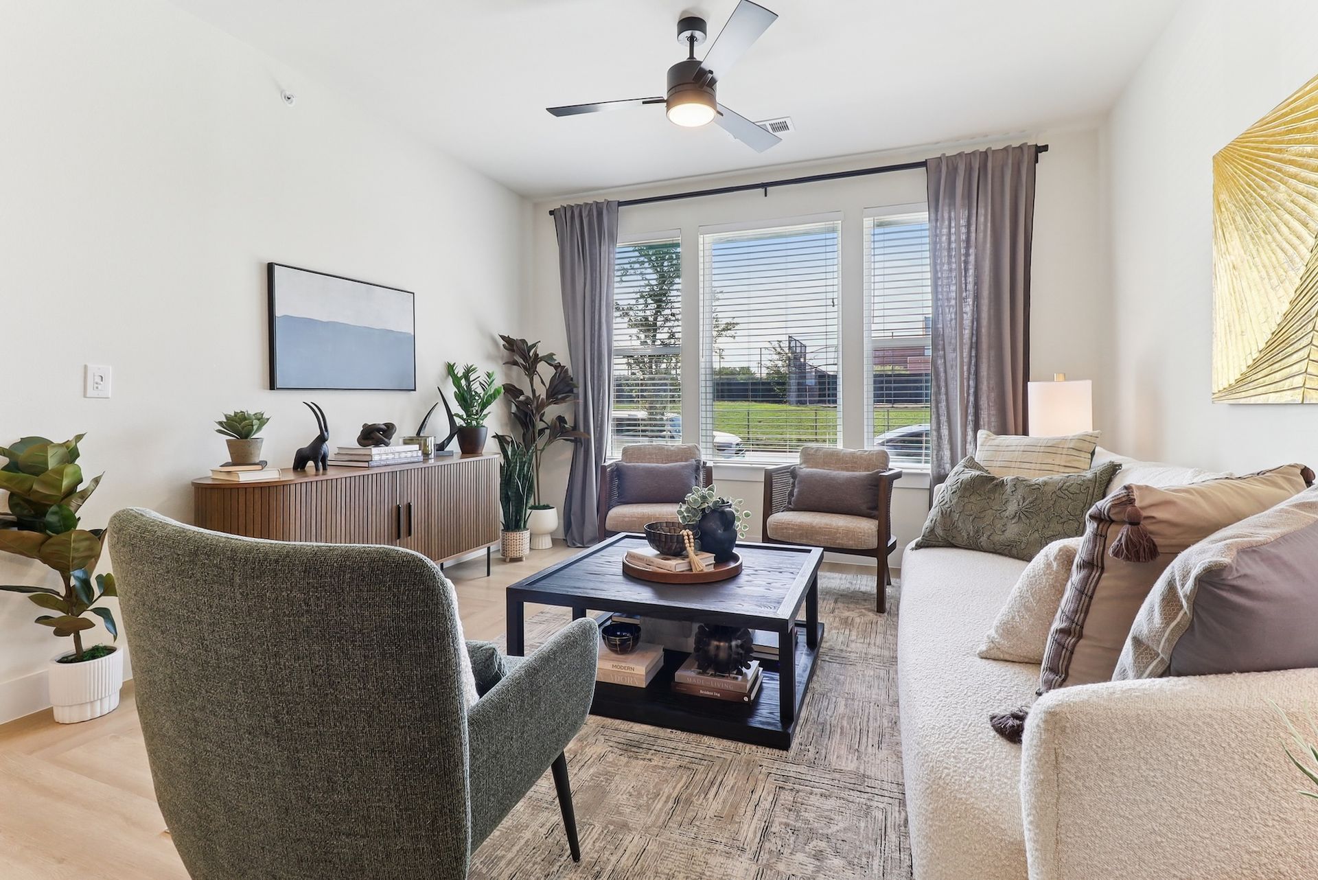 A living room with a couch , chairs , coffee table and ceiling fan.