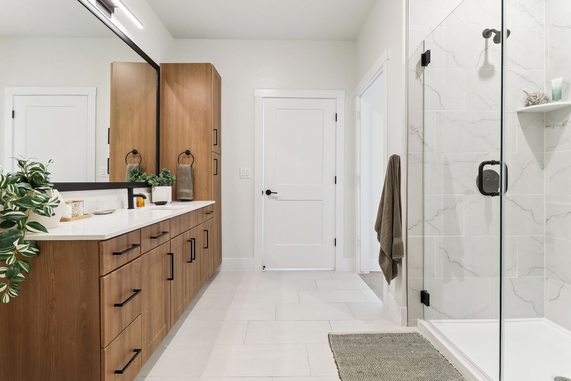 A bathroom with a walk in shower and a double sink.