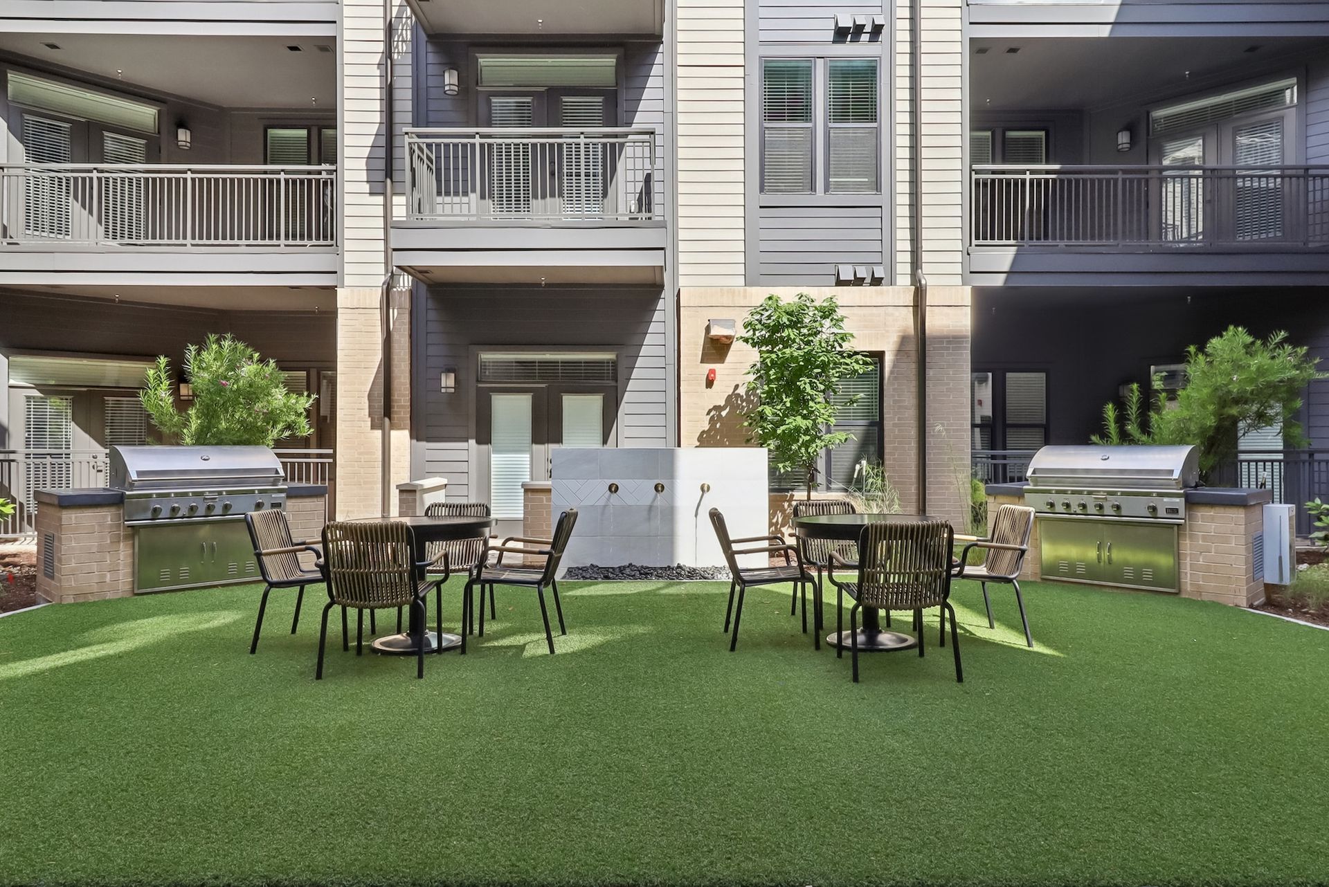 A rendering of a patio area with tables and chairs in front of a building.
