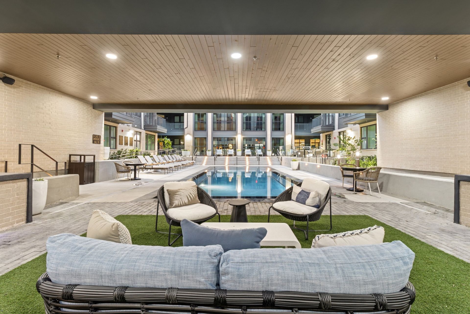 A living room with a couch , chairs , tables and a swimming pool.