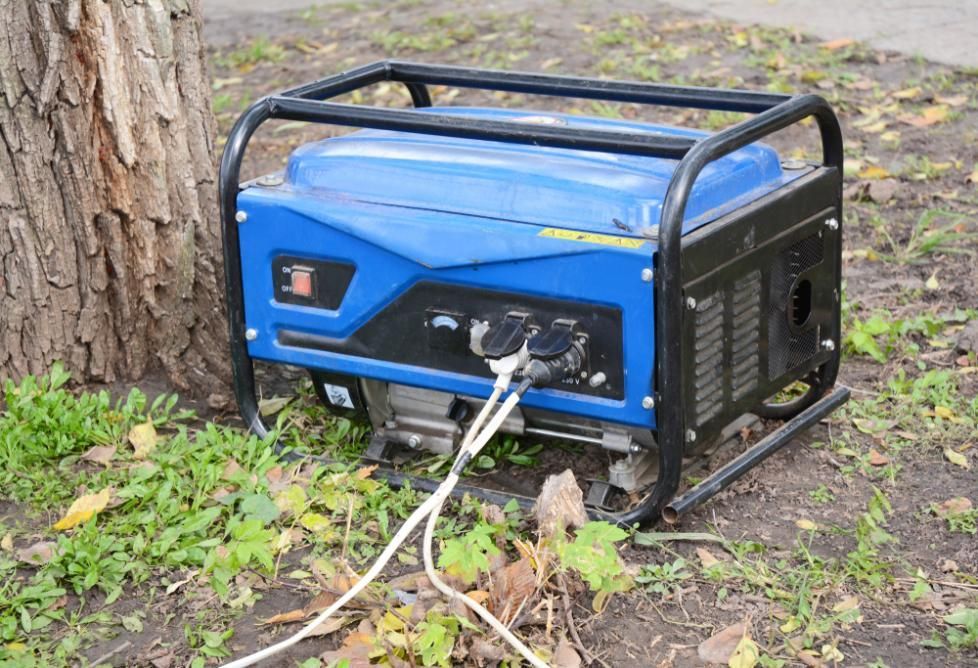 A Blue Generator Is Sitting In The Grass Next To A Tree — Whitsunday Mowers In Cannonvale, QLD