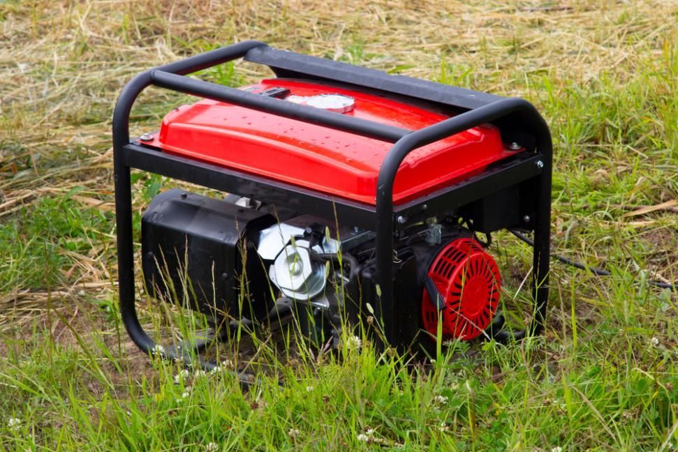 A Red Portable Generator Is Sitting In The Grass — Whitsunday Mowers In Airlie Beach, QLD