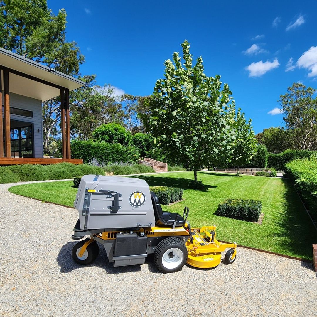 A Lawn Mower With A Trailer Attached To It Is Parked In A Grassy Field — Whitsunday Mowers In Proserpine, QLD