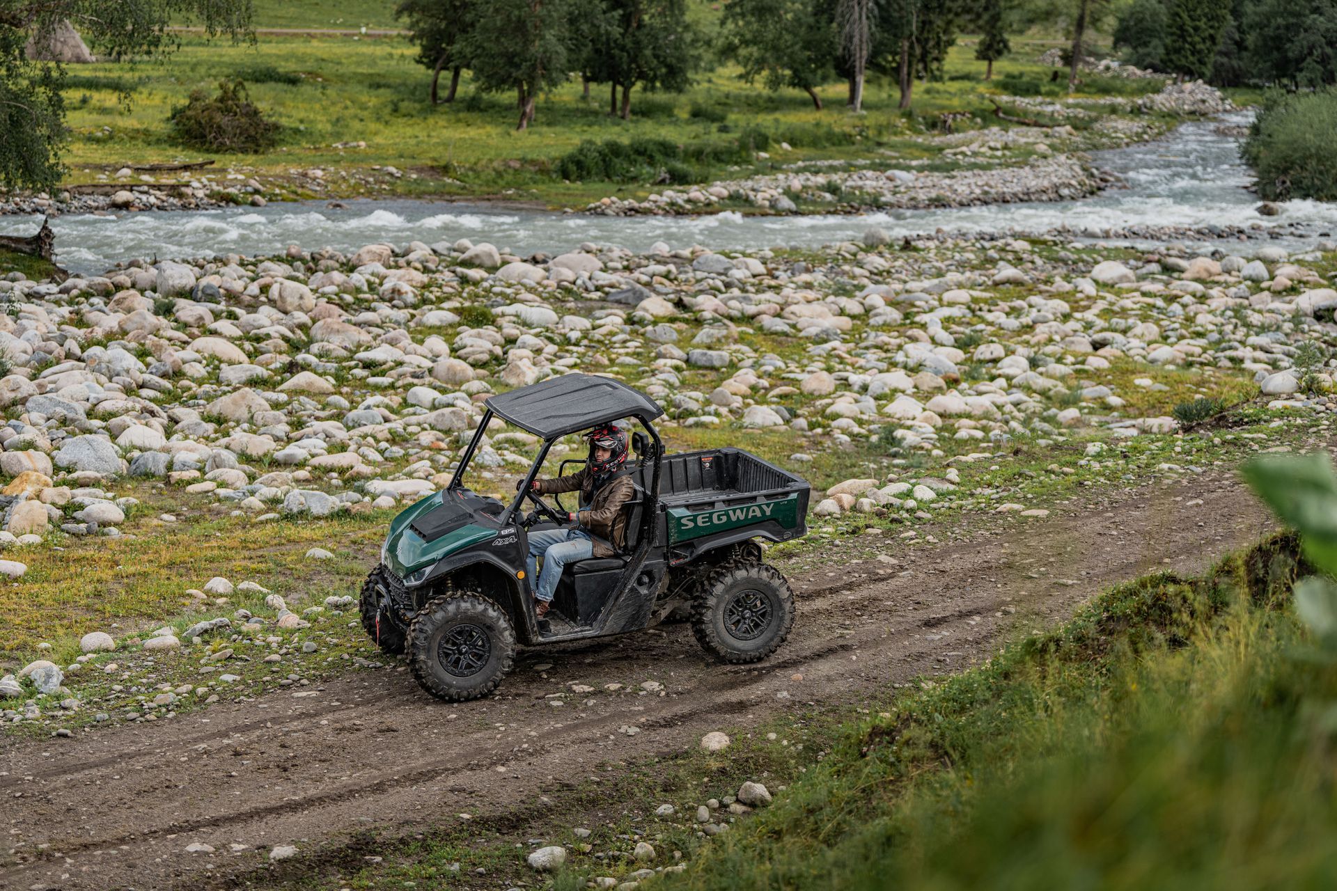 Side-By-Side Atv on A Dirt Path Next to A Rocky River, with Two People Driving — Whitsunday Mowers In Cannonvale, QLD