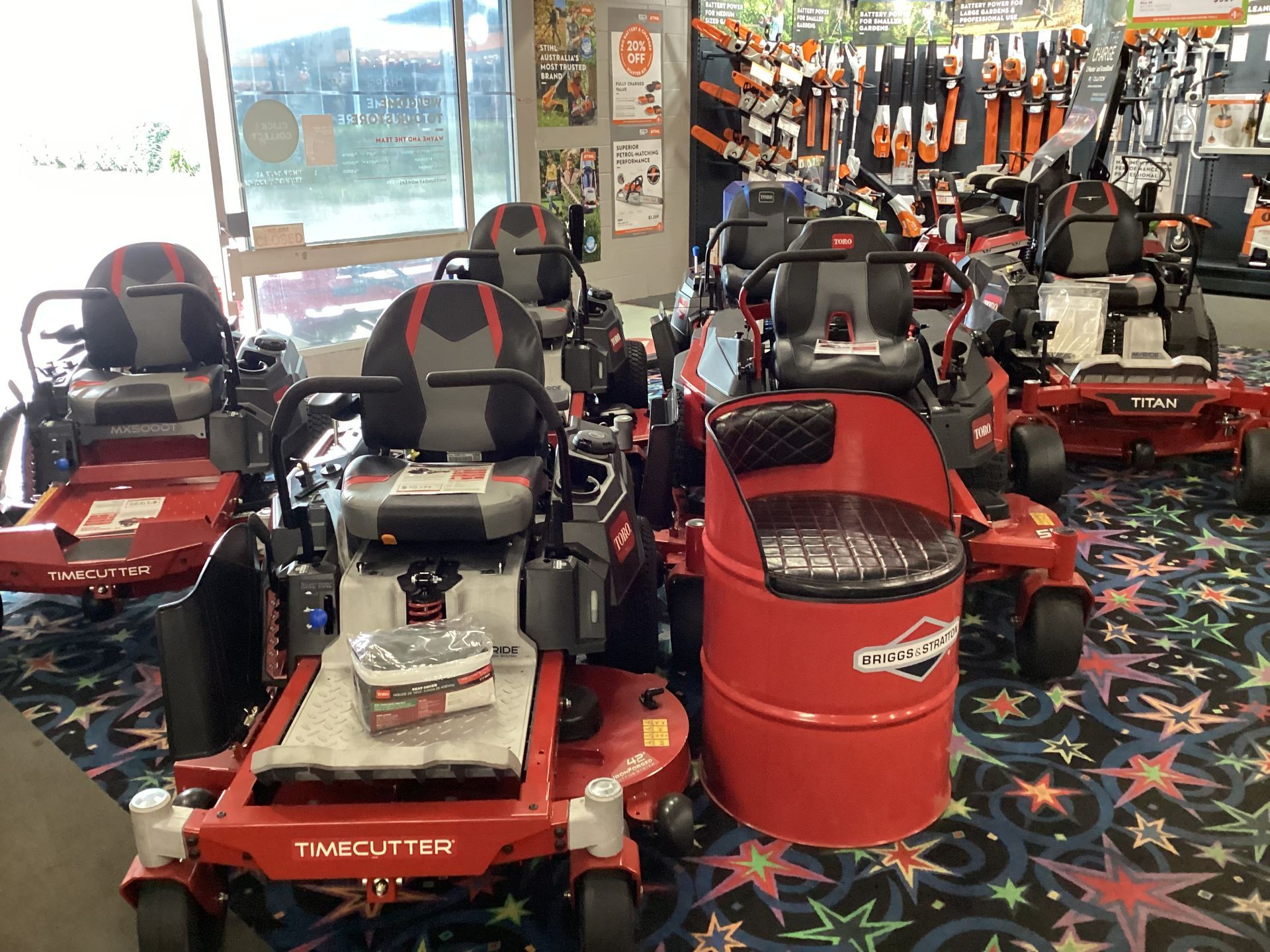 A Man Is Riding A Lawn Mower On A Lush Green Field — Whitsunday Mowers In Airlie Beach, QLD