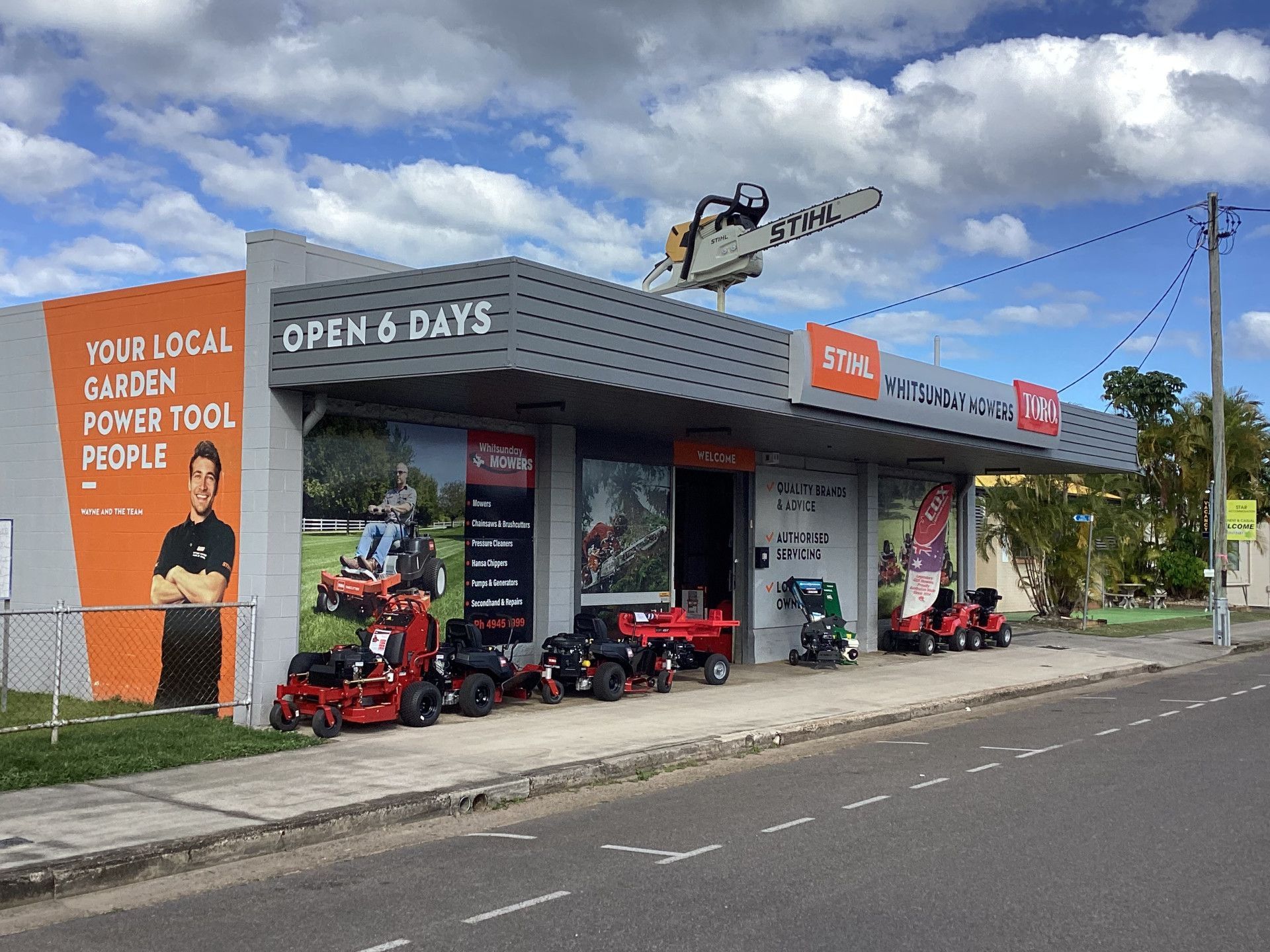 A Man Is Pushing A Lawn Mower On A Lush Green Lawn — Whitsunday Mowers In Cannonvale, QLD