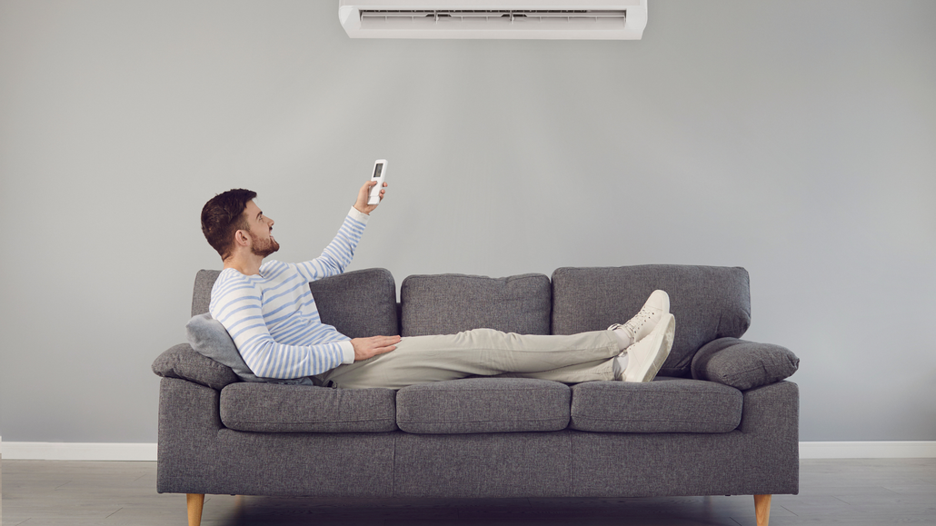 A man is sitting on a couch holding a remote control.