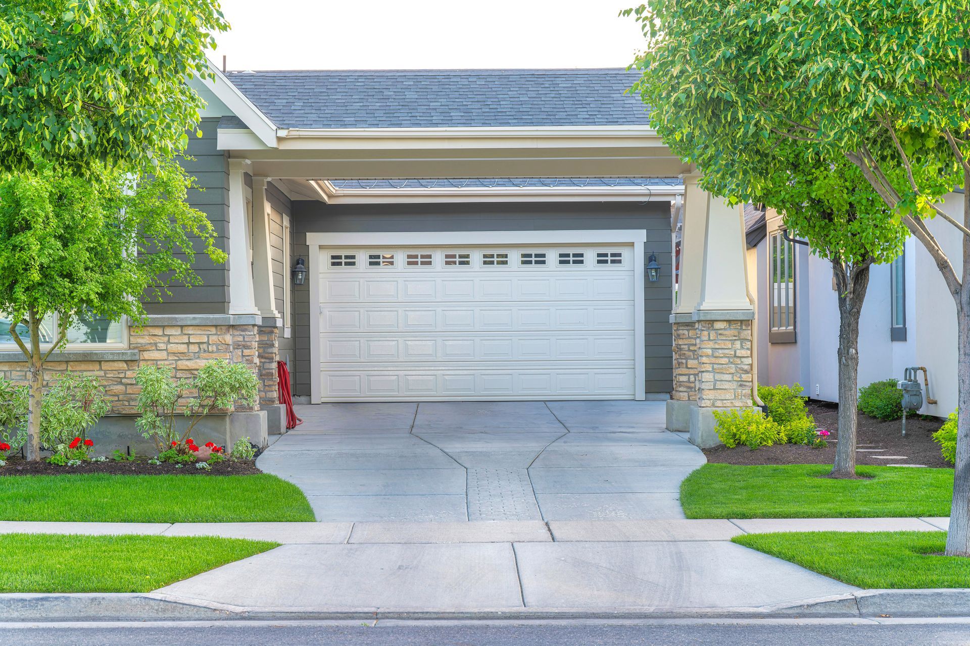 Garage of a house with a concrete driveway intersecting with the sidewalk.