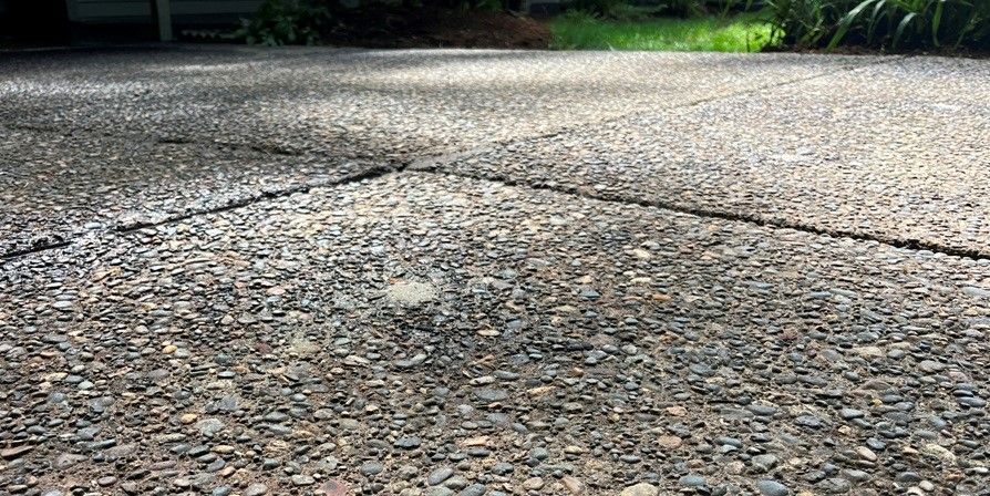 Close-up of a textured concrete surface with visible rocks and a crack.