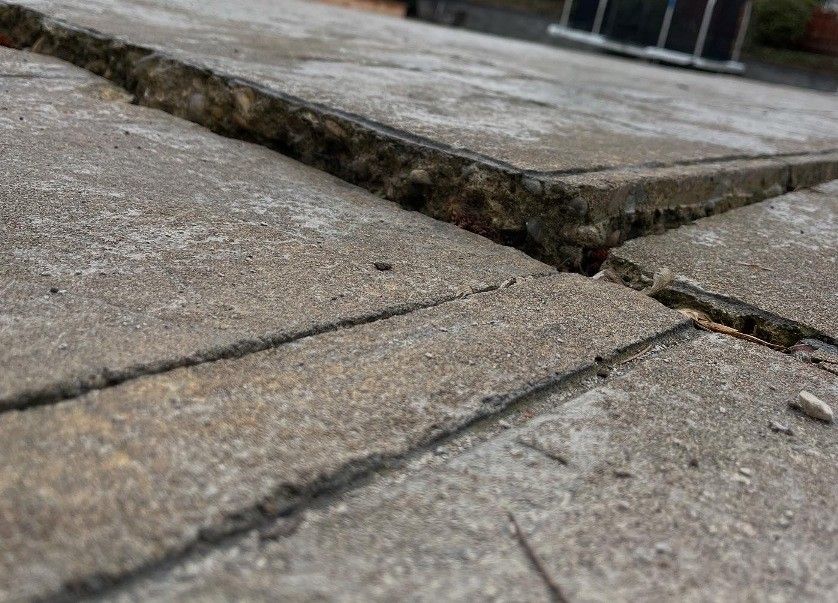 Close-up of cracked concrete tiles on a rooftop, showing gaps and weathering.