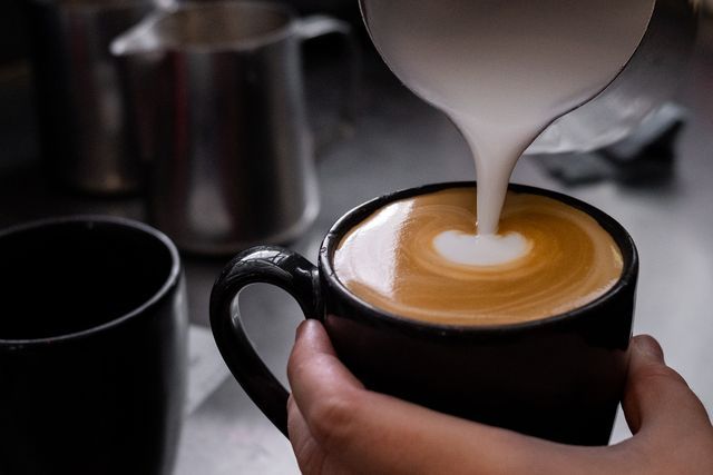 Person is Pouring Milk Into a Cup of Coffee — Chop ‘n Chill Raby Bay in Cleveland, QLD