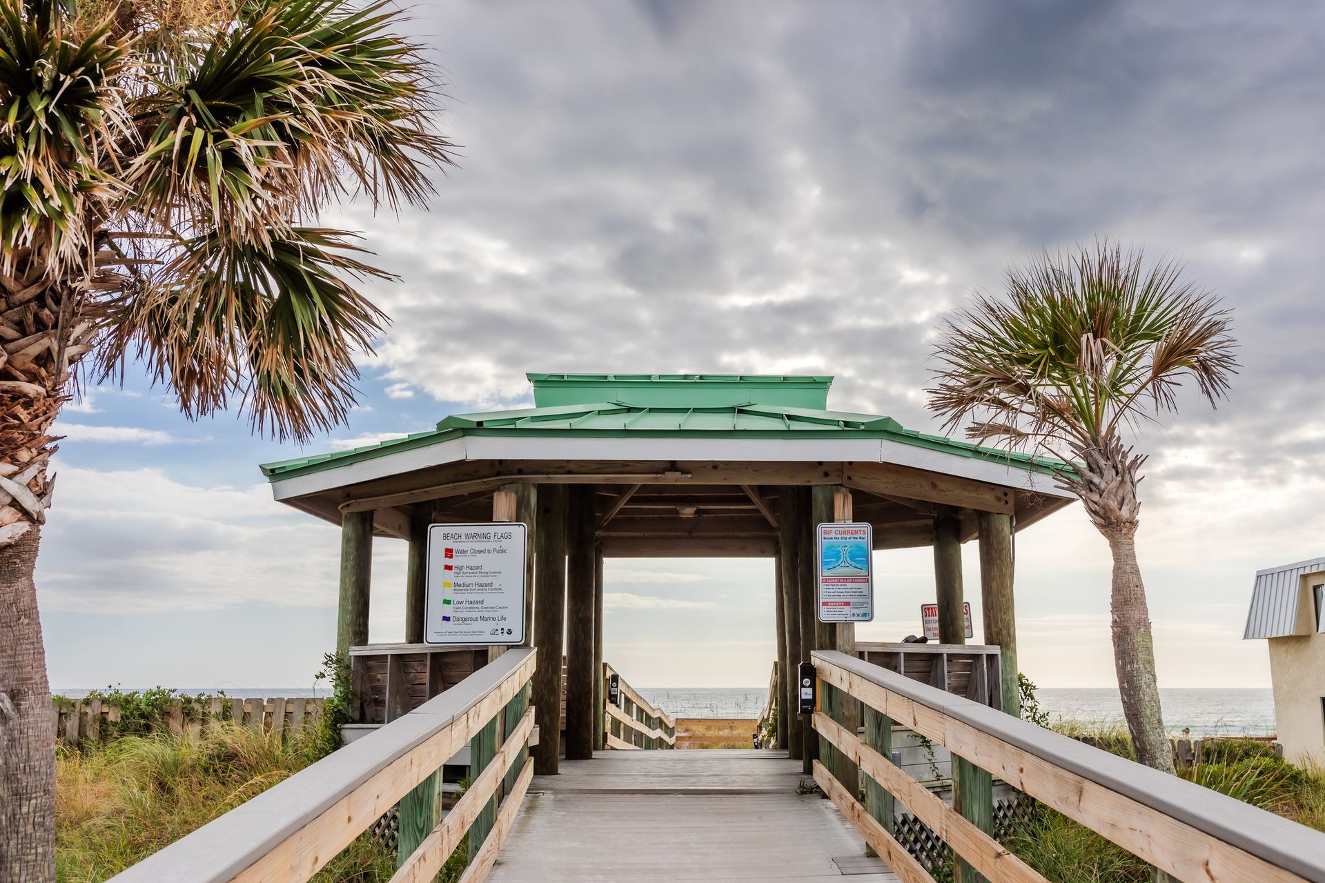 A wooden walkway leading to the beach with palm trees.