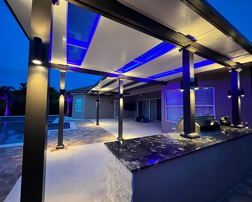 A patio with a covered area and a marble counter top at night.