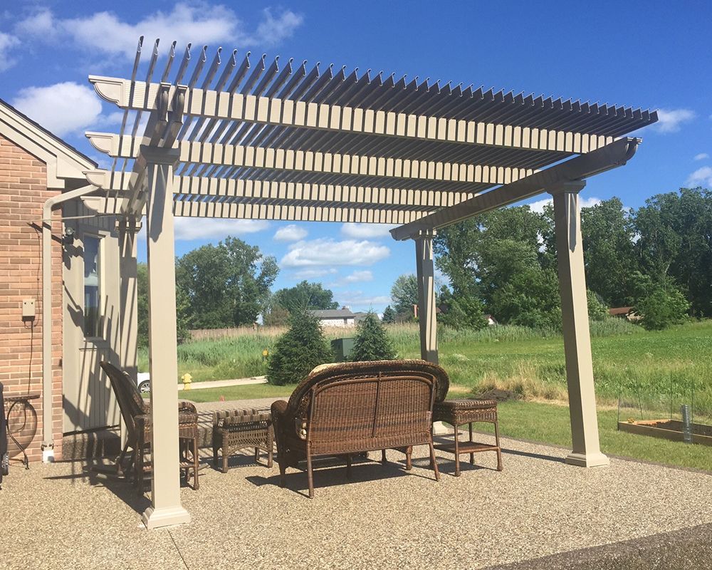 A pergola with a couch and chairs underneath it