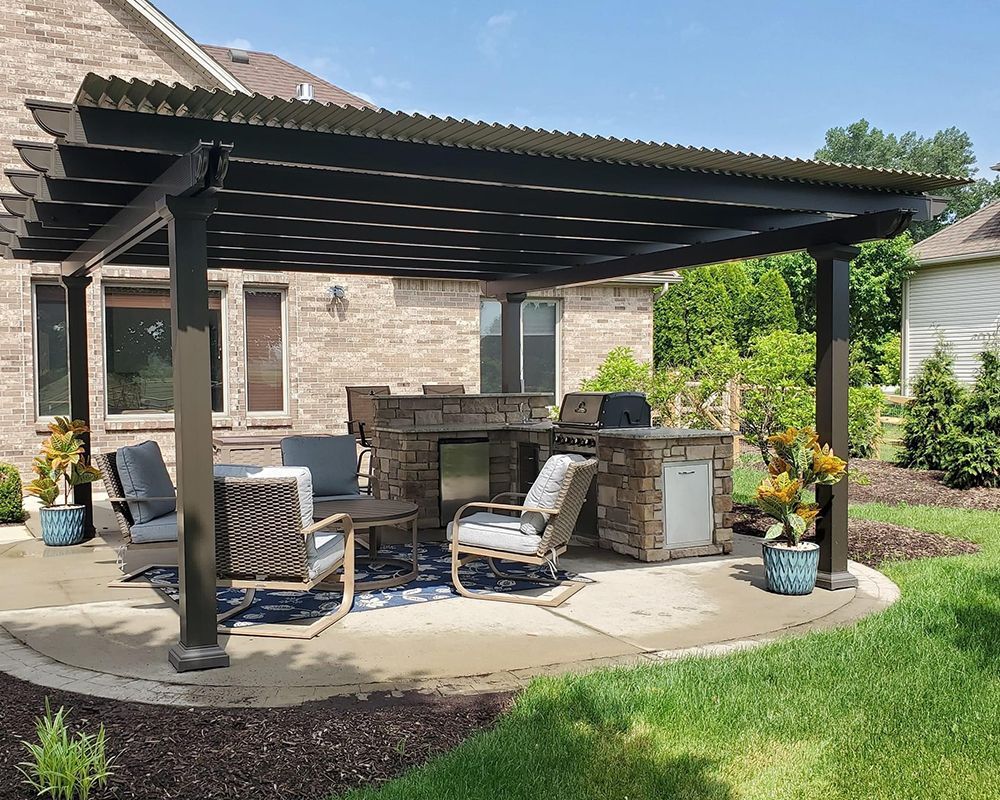 A patio with a pergola and a kitchen in the backyard of a house.