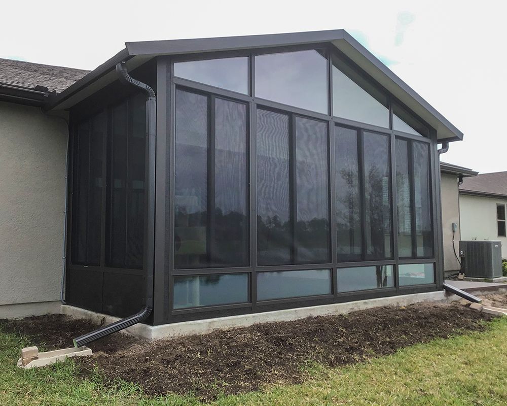 A screened in porch on the side of a house.