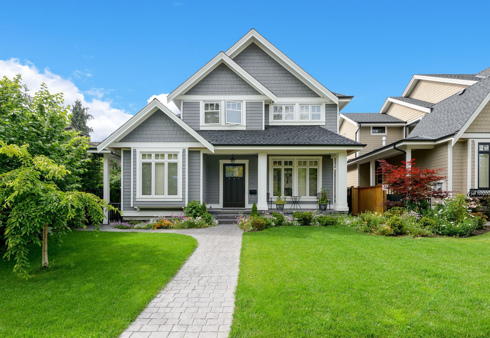 A large house with a lush green lawn and a walkway leading to it.