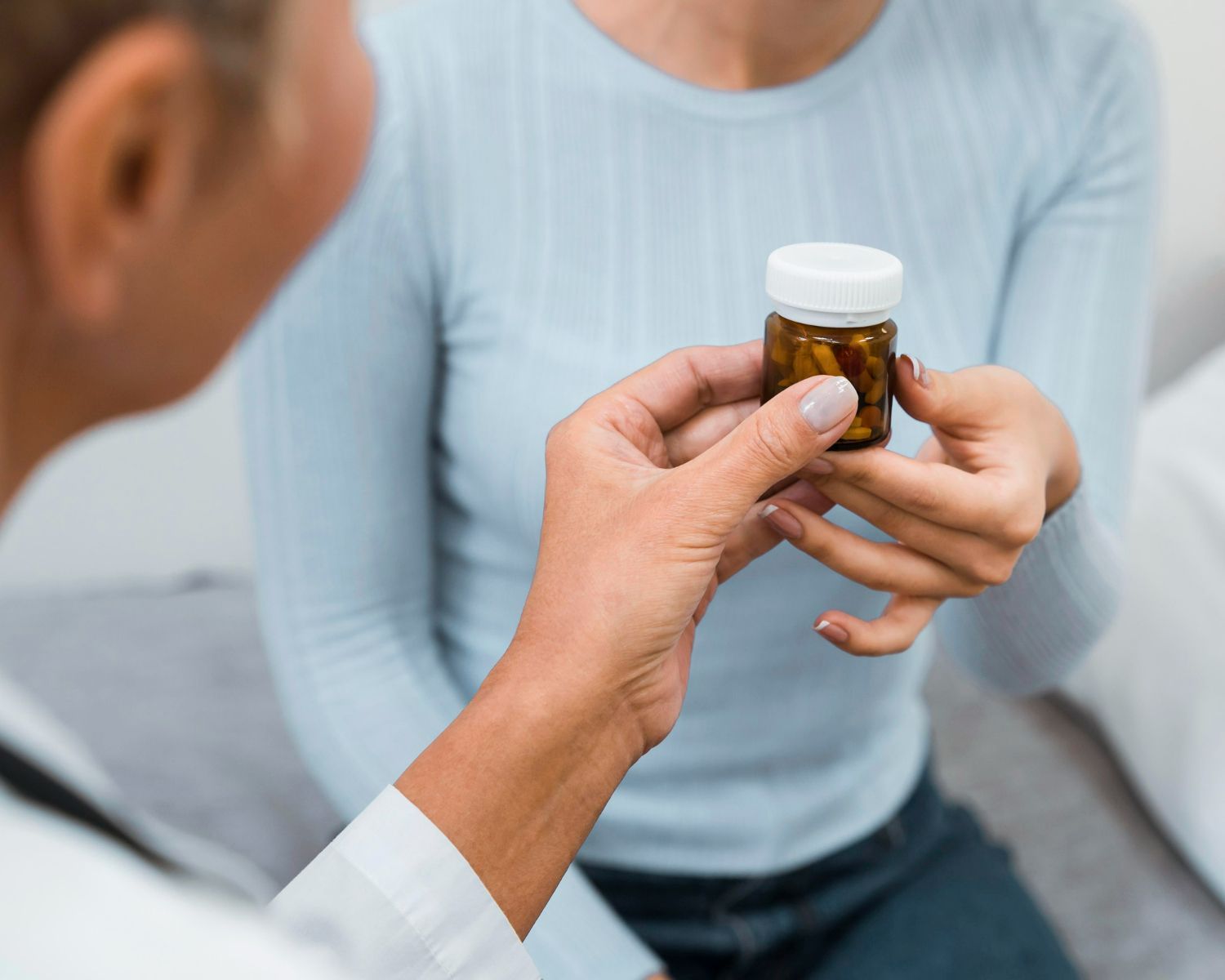 A doctor is giving a bottle of pills to a patient.