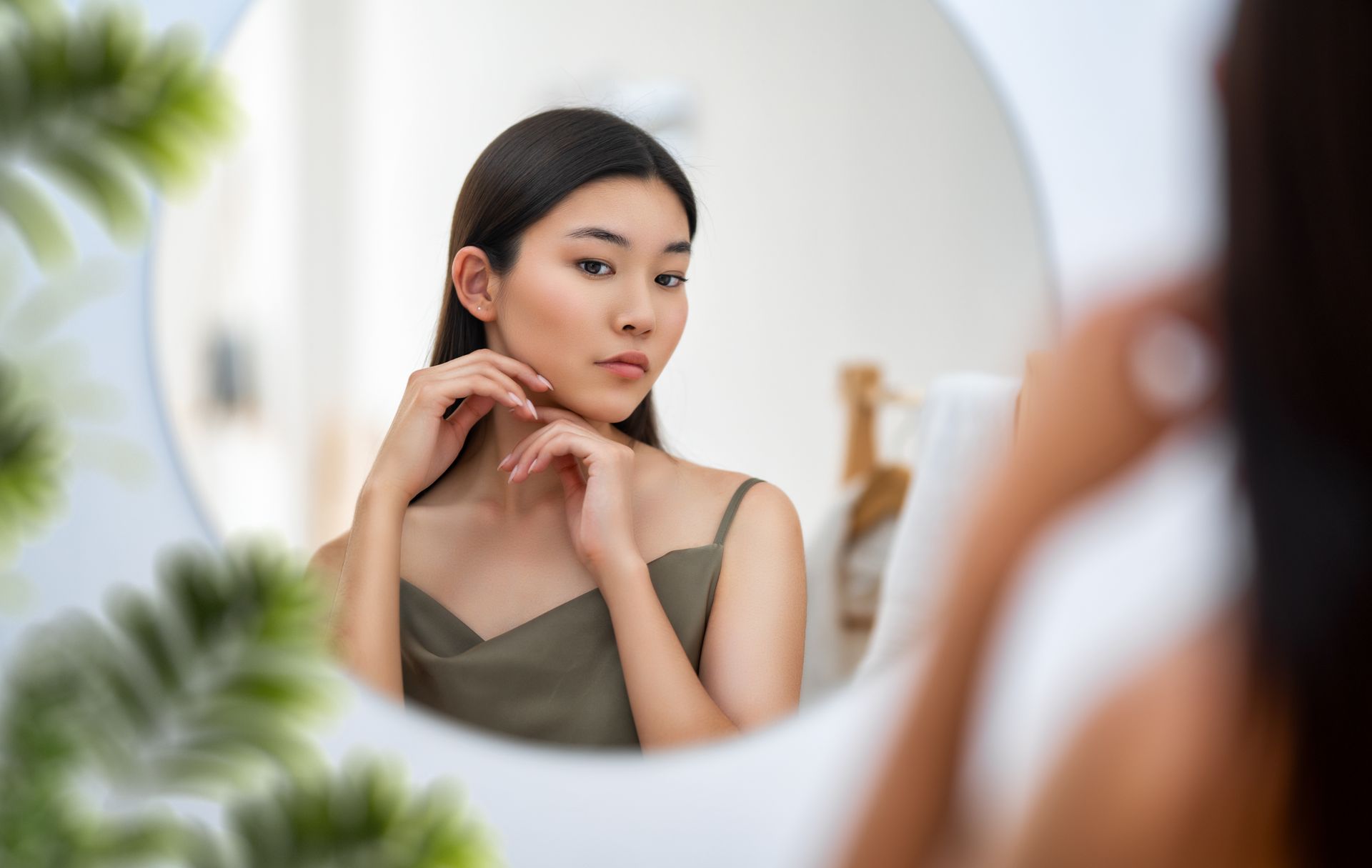 woman looking at mirror touching face