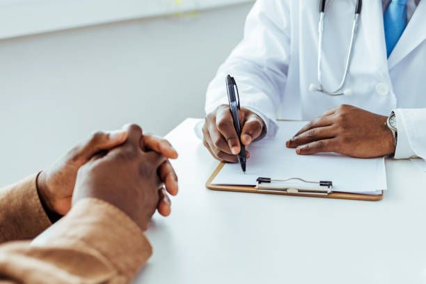 A doctor is writing on a clipboard while talking to a patient