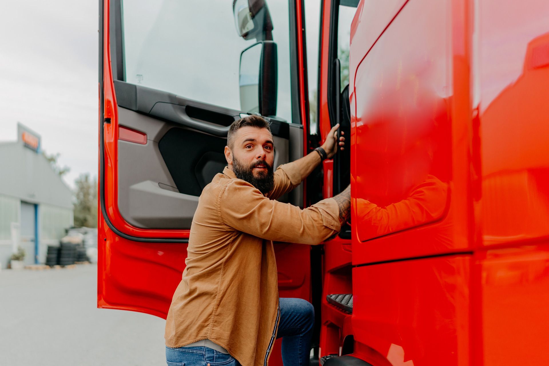 A man with a beard is getting out of a red truck