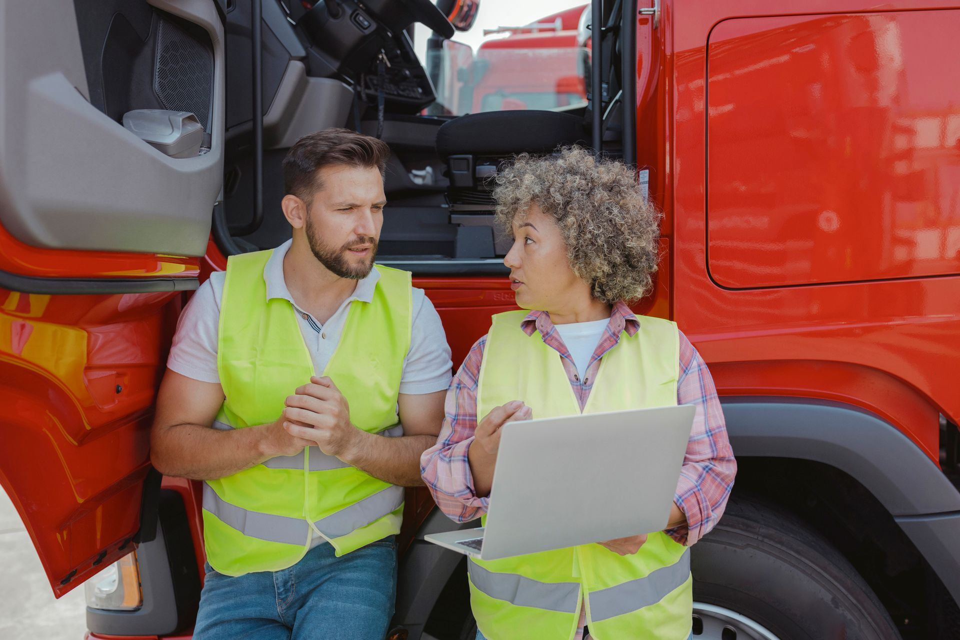 A man in a yellow vest is standing in front of a row of red trucks