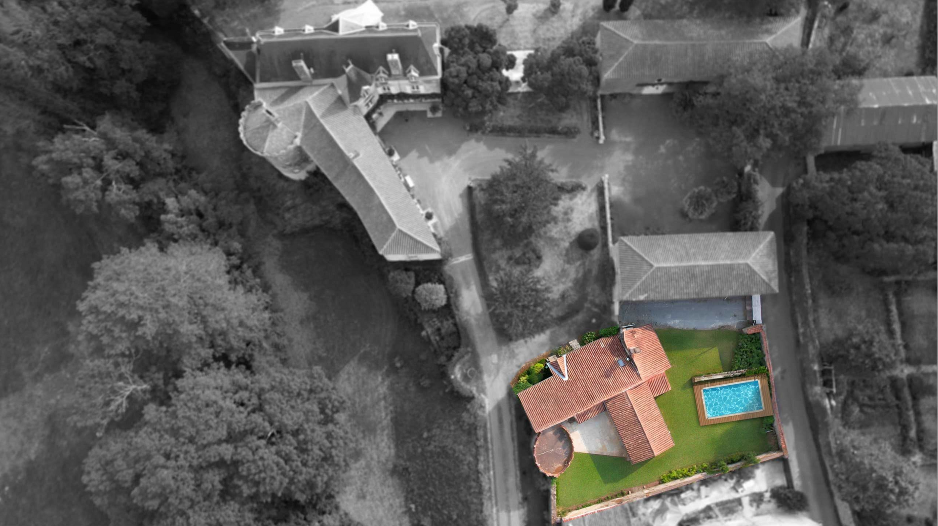 Aerial view of a building with an orange roof and green yard surrounded by black and white buildings and trees.