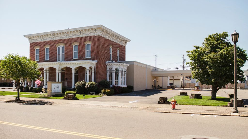 A large brick building with white trim sits on the corner of a street.