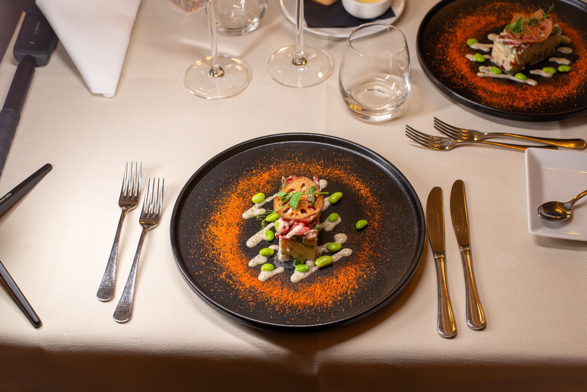 Elegante tafeldekking met borden met eten, bestek en wijnglazen.