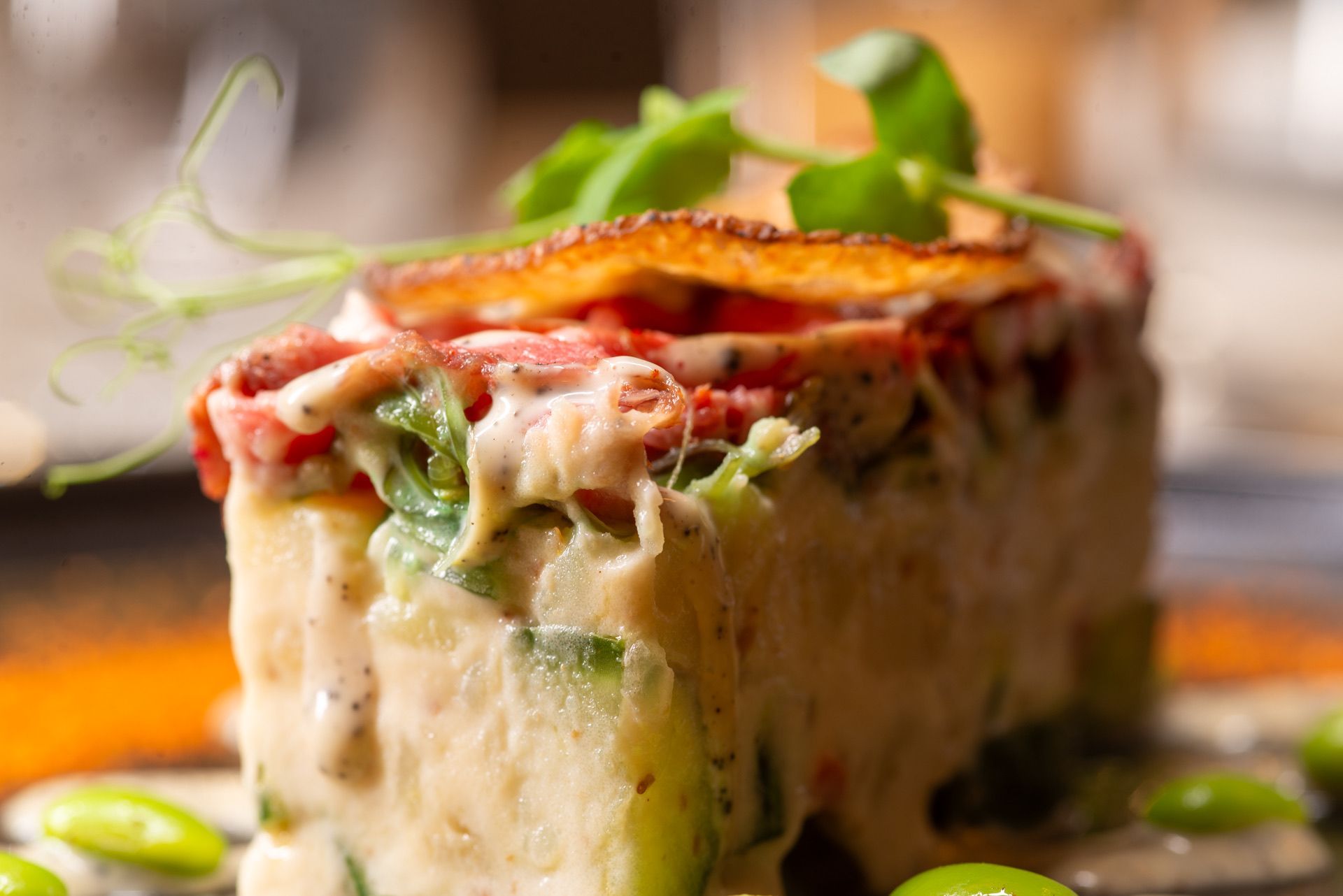 Romige rechthoekige voedselschaal met groen erop, omringd door groene erwten.