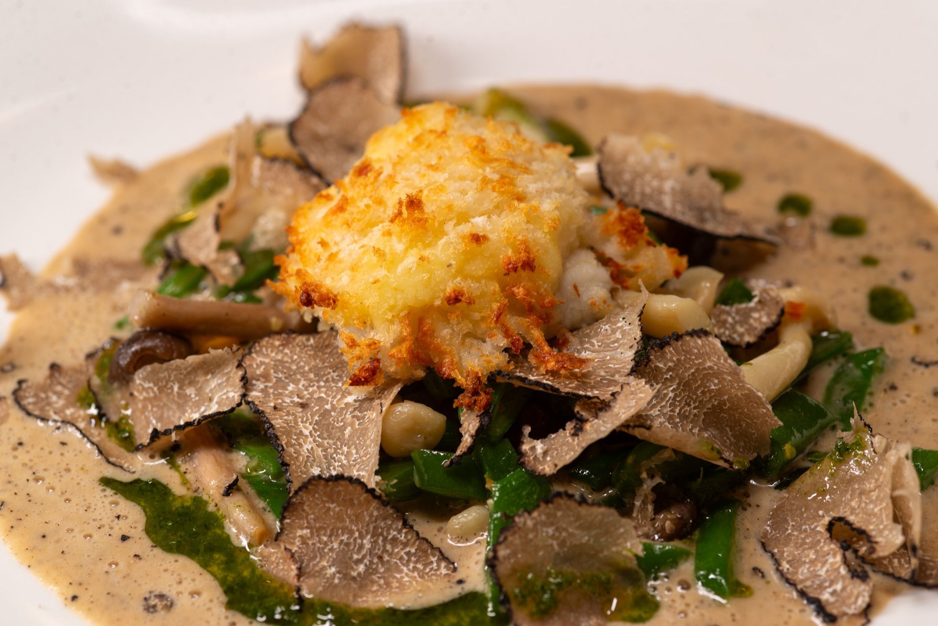 Romige paddenstoelenschotel met truffelschaafsel en een goudbruine korst in het midden.