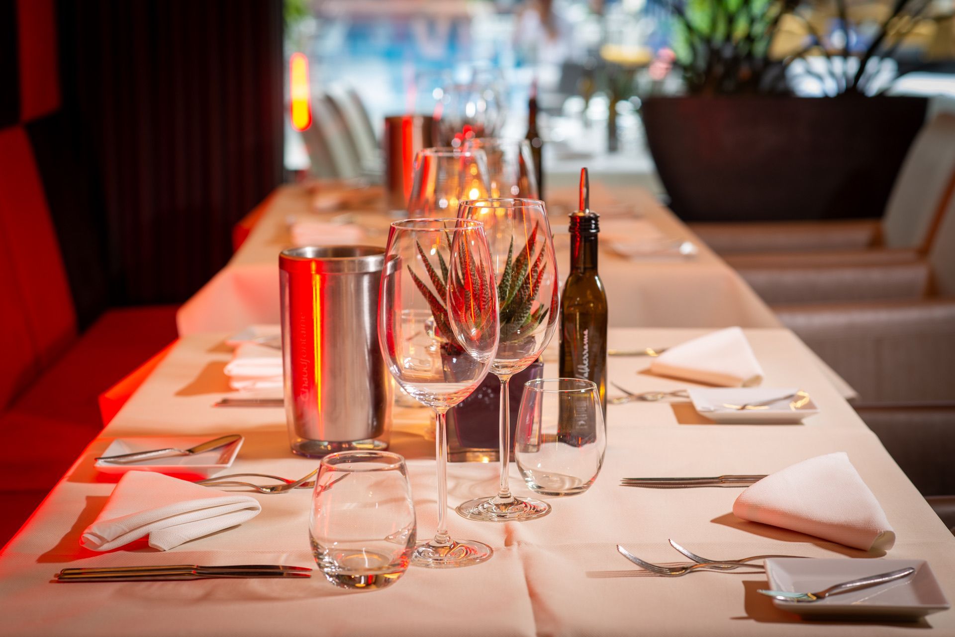 De tafel in een restaurant is gedekt voor een maaltijd: glazen, bestek, servetten en een fles wijn.