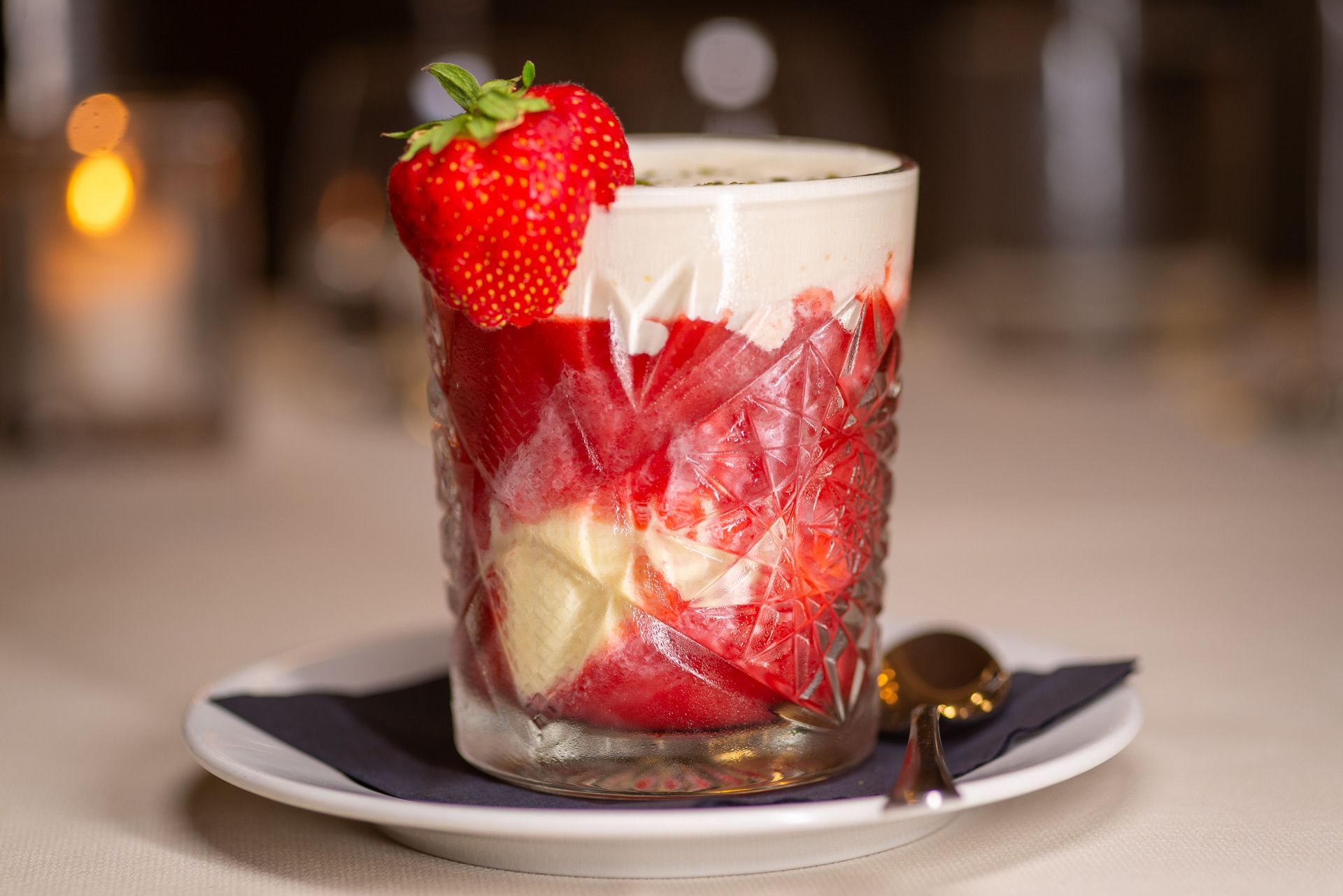 Aardbeiendessert in een decoratief glas met een hele aardbei als garnering.