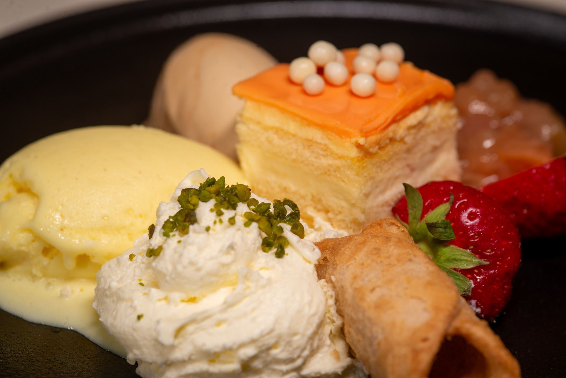 Dessertbord met ijs, baklava, slagroom, aardbei en wafelrol.