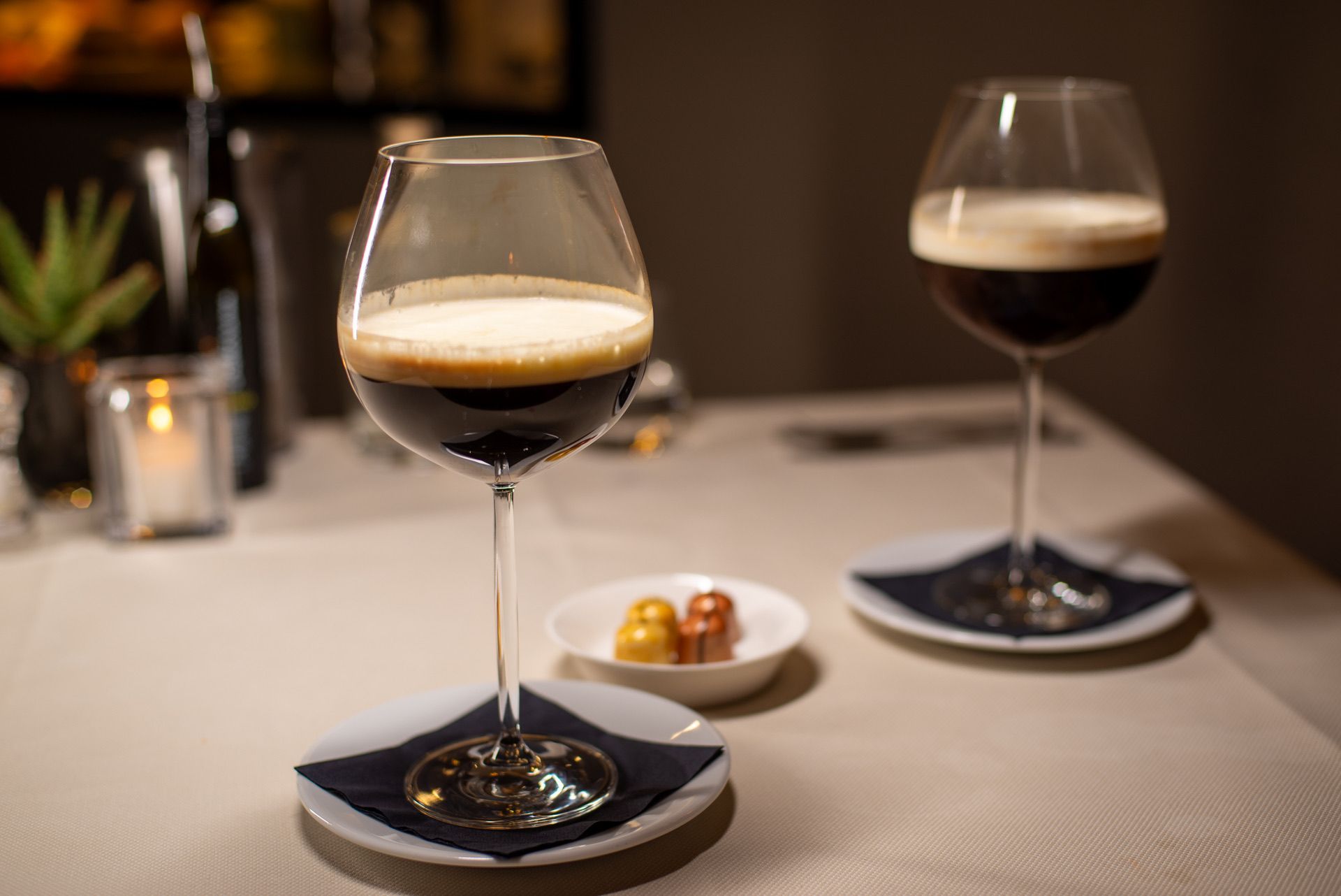 Twee glazen donker stoutbier met schuimkraag op tafel. Een klein bordje olijven.