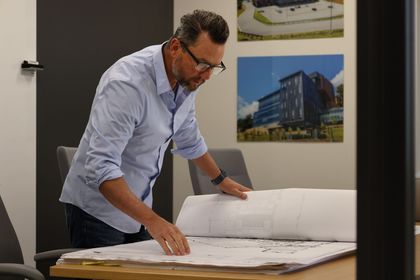 A man is looking at a blueprint on a table.