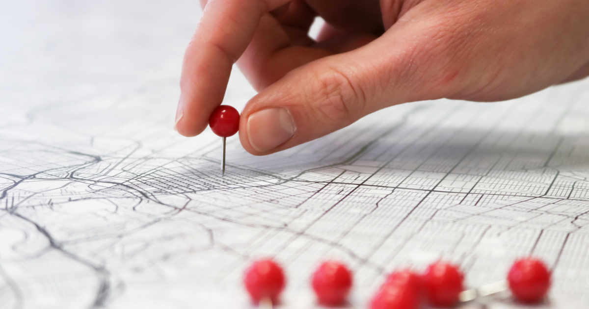A person putting a pin on a map