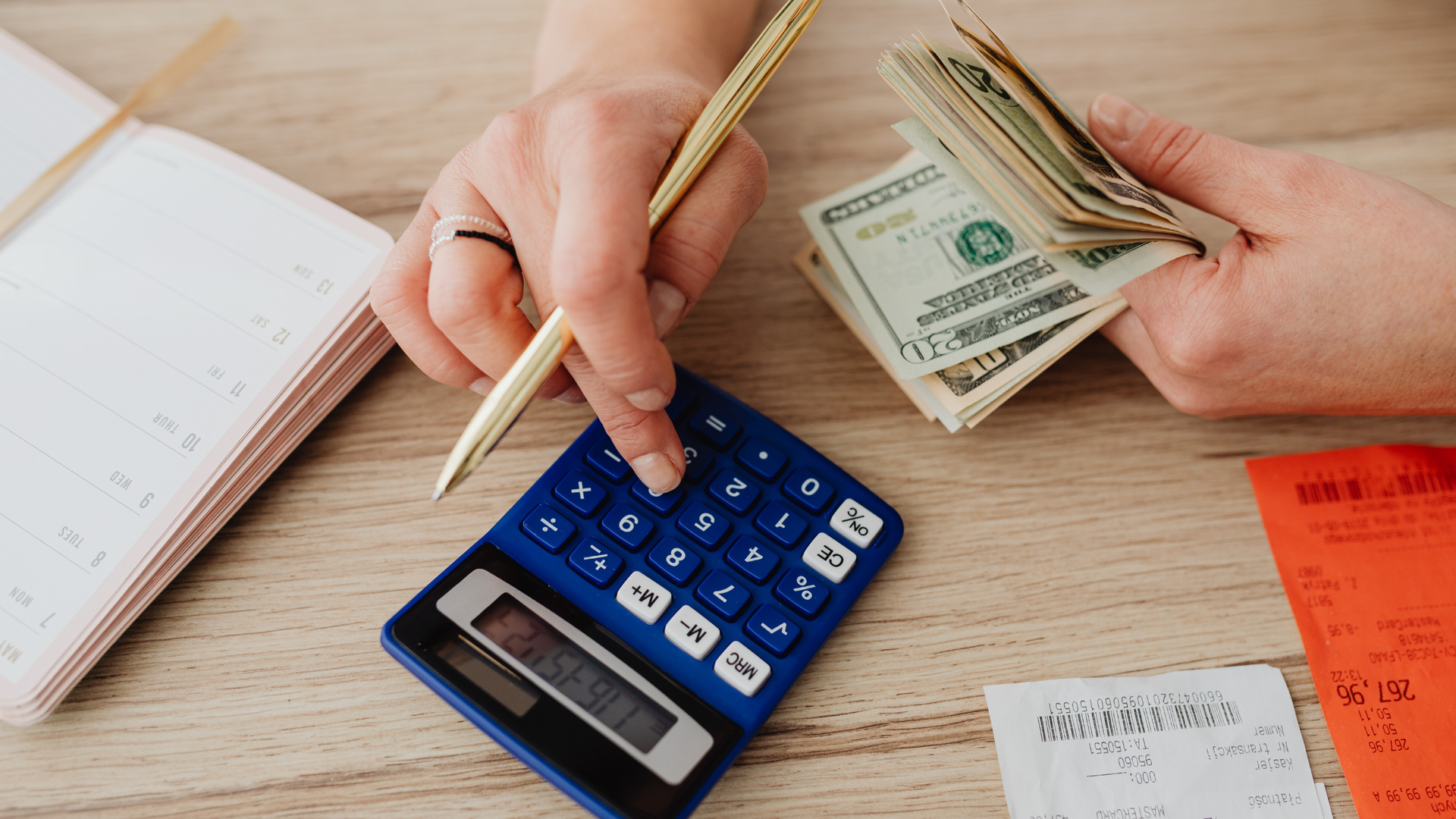 someone holding money in one had, and using a calculator with the other, while holding a gold pen