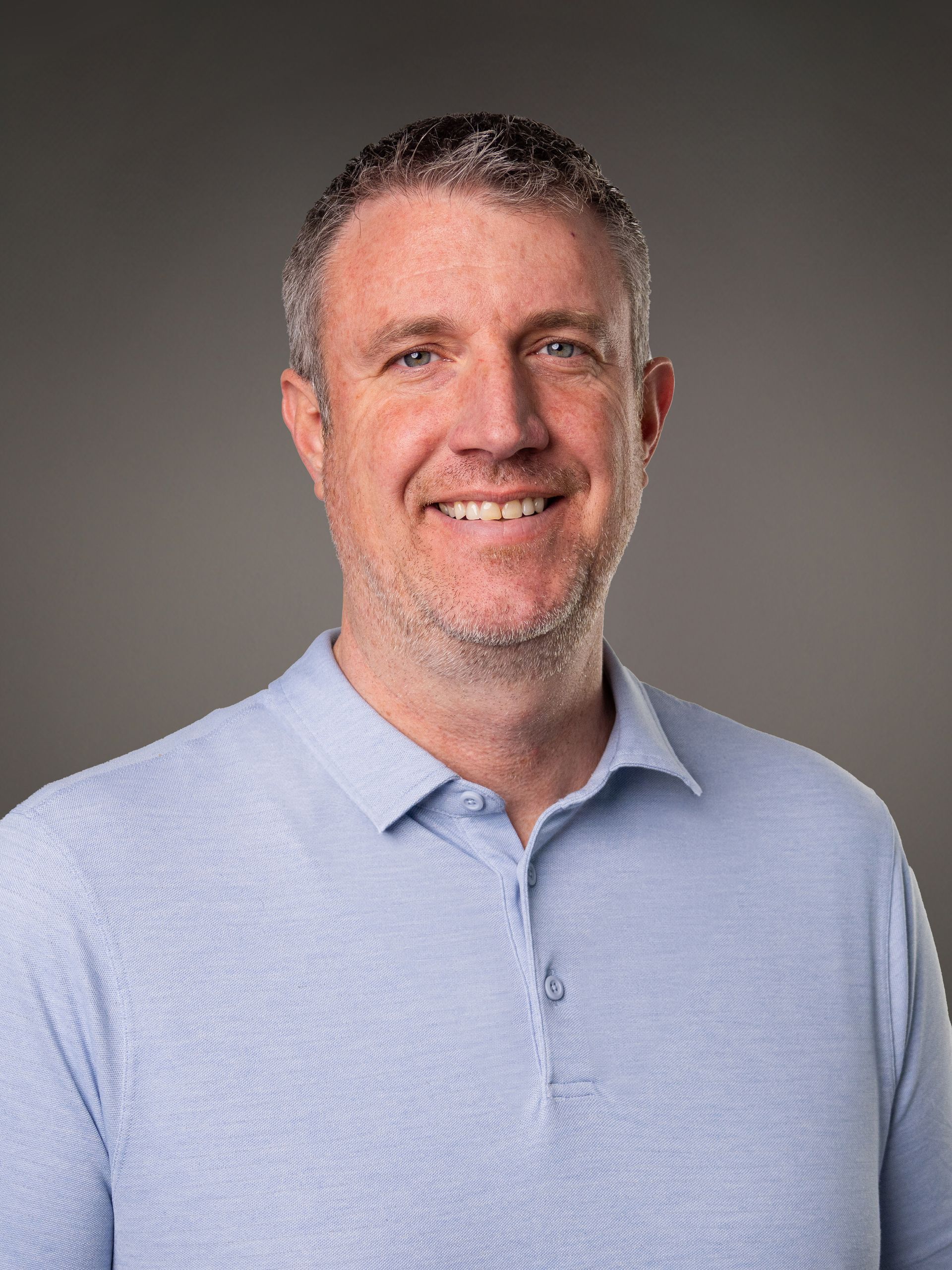 A man with a beard is smiling for the camera with his arms crossed.