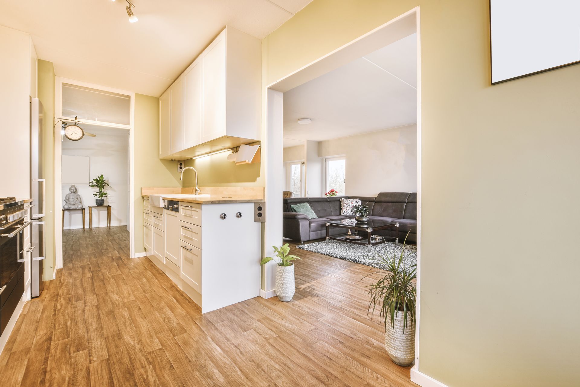 A kitchen with wooden floors and white cabinets is open to a living room.